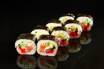 Traditional sushi roll with salmon, cream cheese, caviar and cucumber on black stone. Japanese food
