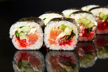 Traditional sushi roll with salmon, cream cheese, caviar and cucumber on black stone. Japanese food