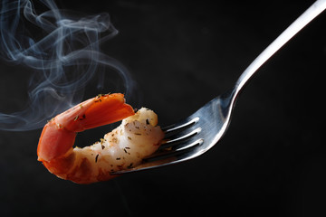  King shrimp on fork  at black background. Close up.