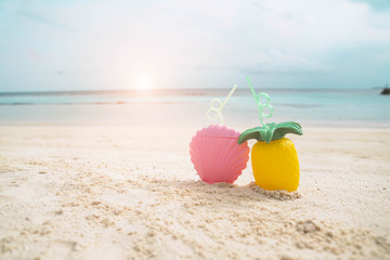 Exotic tropical summer drinks in pink shell shaped and pineapple shaped  bottle on the sandy beach background, Maldives