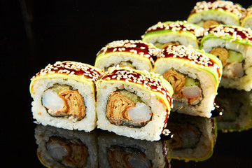 Traditional sushi roll with shrimps, cream cheese and egg omlet on black stone. Japanese food