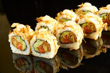Traditional sushi roll with salmon, cream cheese and cucumber on black stone. Japanese food