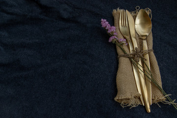 A set of bronze cutlery, spoon, fork and knife black background.