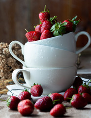 Fresh strawberry in white ceramic cup on wood table with nature light for food issue.