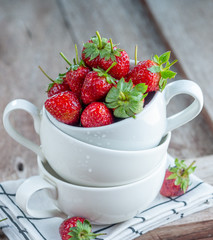 Fresh strawberry in white ceramic cup on wood table with nature light for food issue.