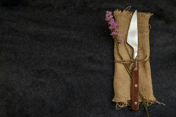 Vintage cutlery knife and flower on black background.