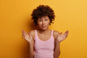 Photo of confused unaware woman raises palms with hesitation, faces difficult choice, has...