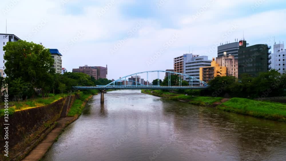 Poster kumamoto, japan. view of a bridge over the shirakawa river in kumamoto, japan time-lapse at sunset w