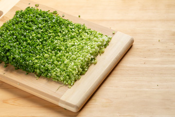 Fresh slice spring onion on wood cutting board, on wood table all green color for food issue with copy space.
