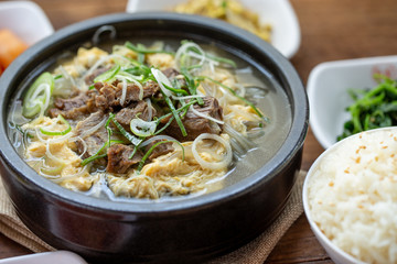 One big set of galbitang, korean style beef soup, serve with many slide dish and rice on wood table with nature light. For food issue.