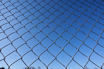 Metal net with blue sky, iron fence on a blue sky, Mesh fence, Chain link fence metal fence and Blue sky background beyond