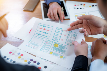 Teamwork graphic designers creative drawing website ux app development and application for mobile phone in the office.