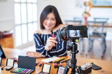 Asian woman blogger blogger with makeup cosmetics recording video clip online.