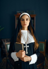 Young nun in a cassock holds book