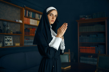 Young nun in a cassock holds book