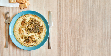 View from above of a plate with melted cheese gratin with the cutlery and some croutons ready to eat