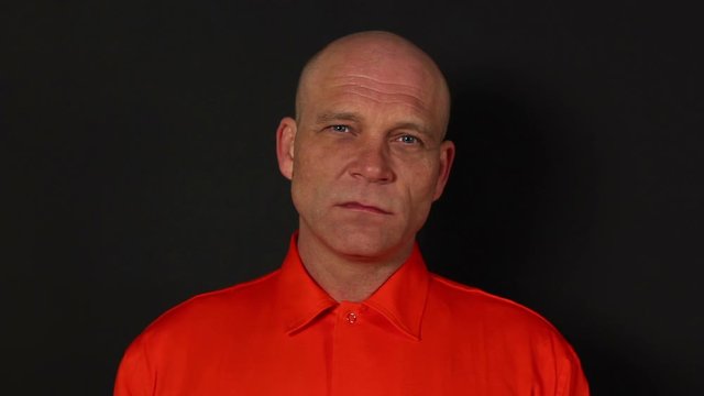 Male Prisoner / Inmate looking at the camera. The criminal is wearing an orange uniform / clothes - Stock Video Clip Footage