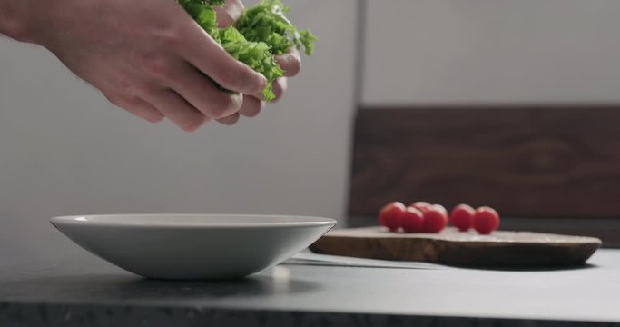 Slow motion add frisee salad leaves into white bowl
