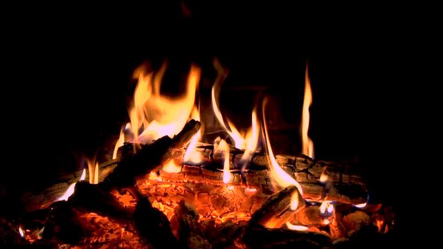 Hot fireplace full of wood. Real Flames from burning logs in slow motion. Fireplace background slowmotion. Fire flame close up.