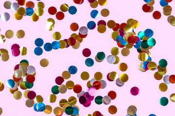Gold colorful confetti of large size on pink background. Festive backdrop of sparkles for birthday, carnival
