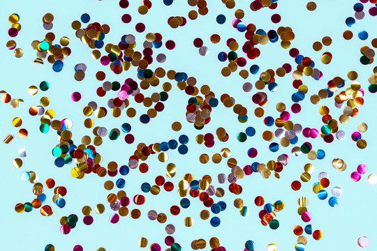 Gold colorful confetti on blue background. Festive backdrop of sparkles for birthday, carnival