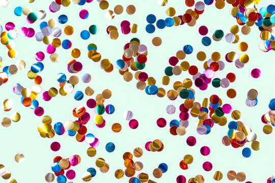 Gold colorful confetti of large size on blue background. Festive backdrop of sparkles for birthday, carnival