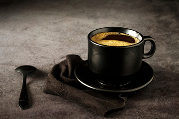 Black coffee cup with coffee on a dark background. With copy space for your text. Cup of coffee on...