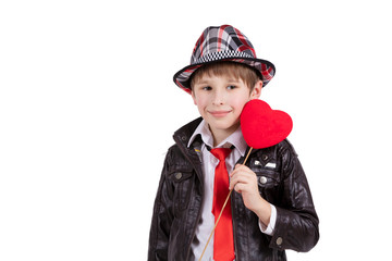 Funny child in an elegant hat holds a heart. Boy with a Valentine.