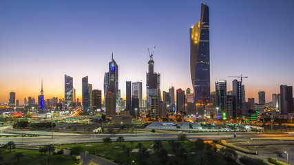 Obraz premium Skyline with Skyscrapers day to night timelapse in Kuwait City downtown illuminated at dusk. Kuwait City, Middle East