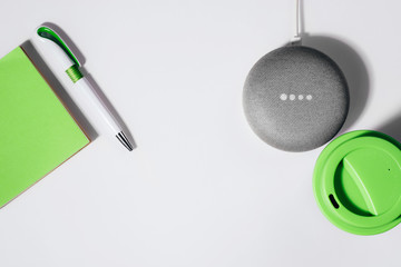 Digital Assistant concept. Flat lay of smart speaker with LED lights activated with cropped green...