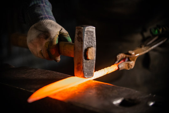 Forging a knife out of the hot metal using a hammer - holding the knife in forceps