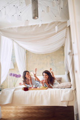 vertical image of two female having breakfast in bed, copy space. lesbian, breakfast, bed, copy space concept © luckybusiness