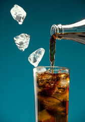 Pieces of ice and carbonated drink pour into a glass