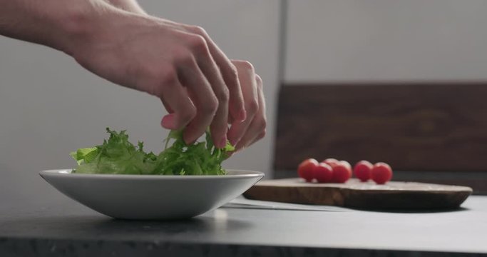 Slow motion add frisee salad leaves into white bowl