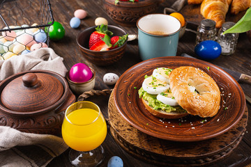 Healthy freshly baked bagel filled with boild eggs, avocado and chives. Breakfast food.