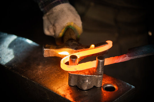 A man blacksmith making a unique handle for the knife - bending the metal