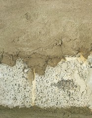 A close up of brick wall partially covered with fresh cement concrete