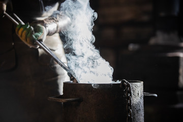 Blacksmith cooling out the detail in bucket filled with cold water