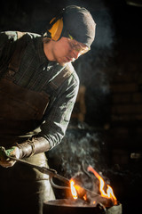 Blacksmith man worker putting a burning item in the bucket of water