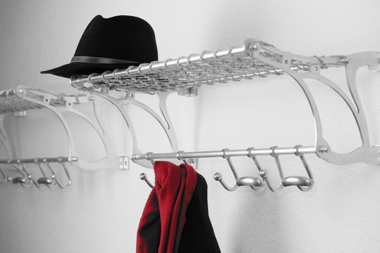 Hut, Mantel und roter Schaal an Gaderobe 