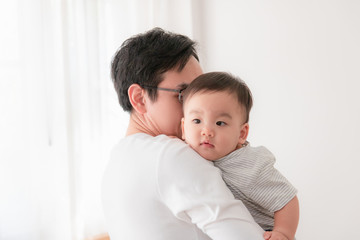 Portrait of an Asian father carrying a baby on his shoulder He shows love for infants. Happy Family Concept