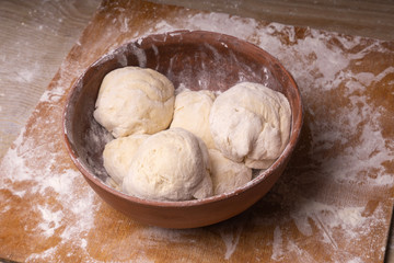 Balls of dough. Plywood cutting board, wooden flour sieve and wooden rolling pin - tools for making dough.
