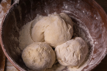 Balls of dough. Plywood cutting board, wooden flour sieve and wooden rolling pin - tools for making dough.