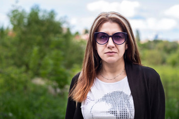 Beautiful but tired and sad woman on park background in her hometown. A woman is tired of problems at work, a very busy schedule of life and needs rest