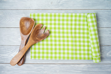Kitchen utensils with green checked tablecloth on rustic wooden table