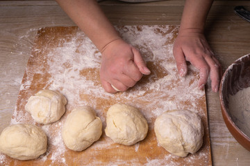 A woman kneads the dough. Plywood cutting board, wooden flour sieve and wooden rolling pin - tools for making dough.