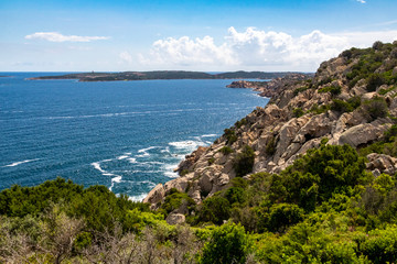 Fototapeta na wymiar Sardinia: Colourful Granite Coastline, Mediterranean Ocean With Capo Ferro, Punta Battistone and Blue Sky – Baia Sardinia, Costa Smerelda, Sardinia, Italy.