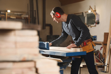 Fototapeta na wymiar Professional carpenter working with surface planer in workshop