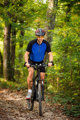 Obraz premium Cyclist riding the bike on the trail in the forest