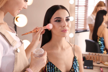 Professional makeup artist working with beautiful woman in salon